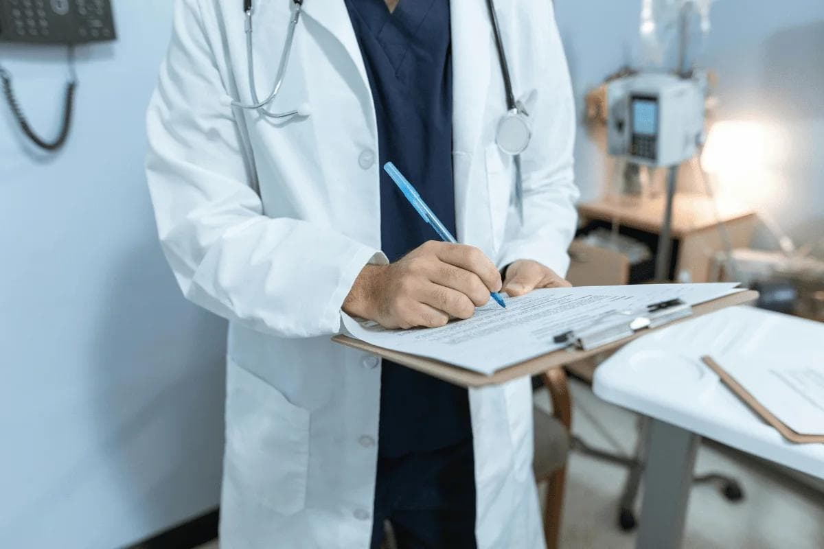 Doctor in white coat filling out medical chart on clipboard.