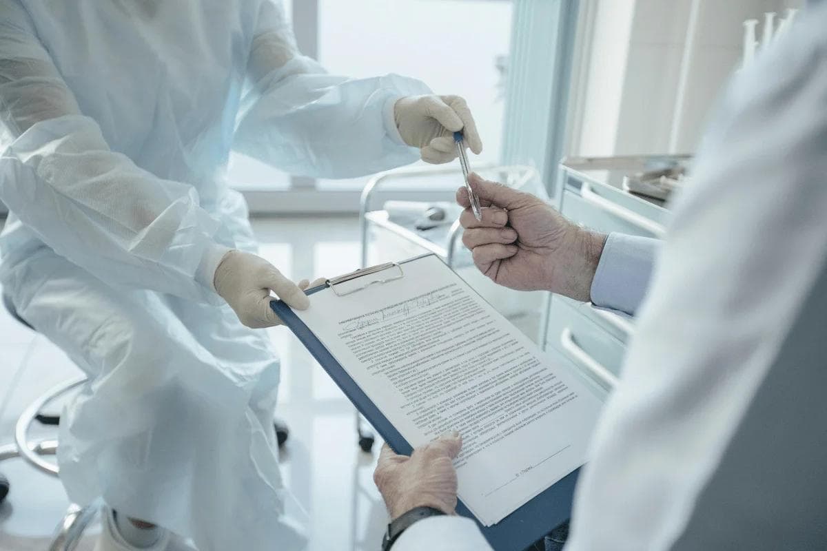 Doctor handing pen to patient to sign a medical consent form.